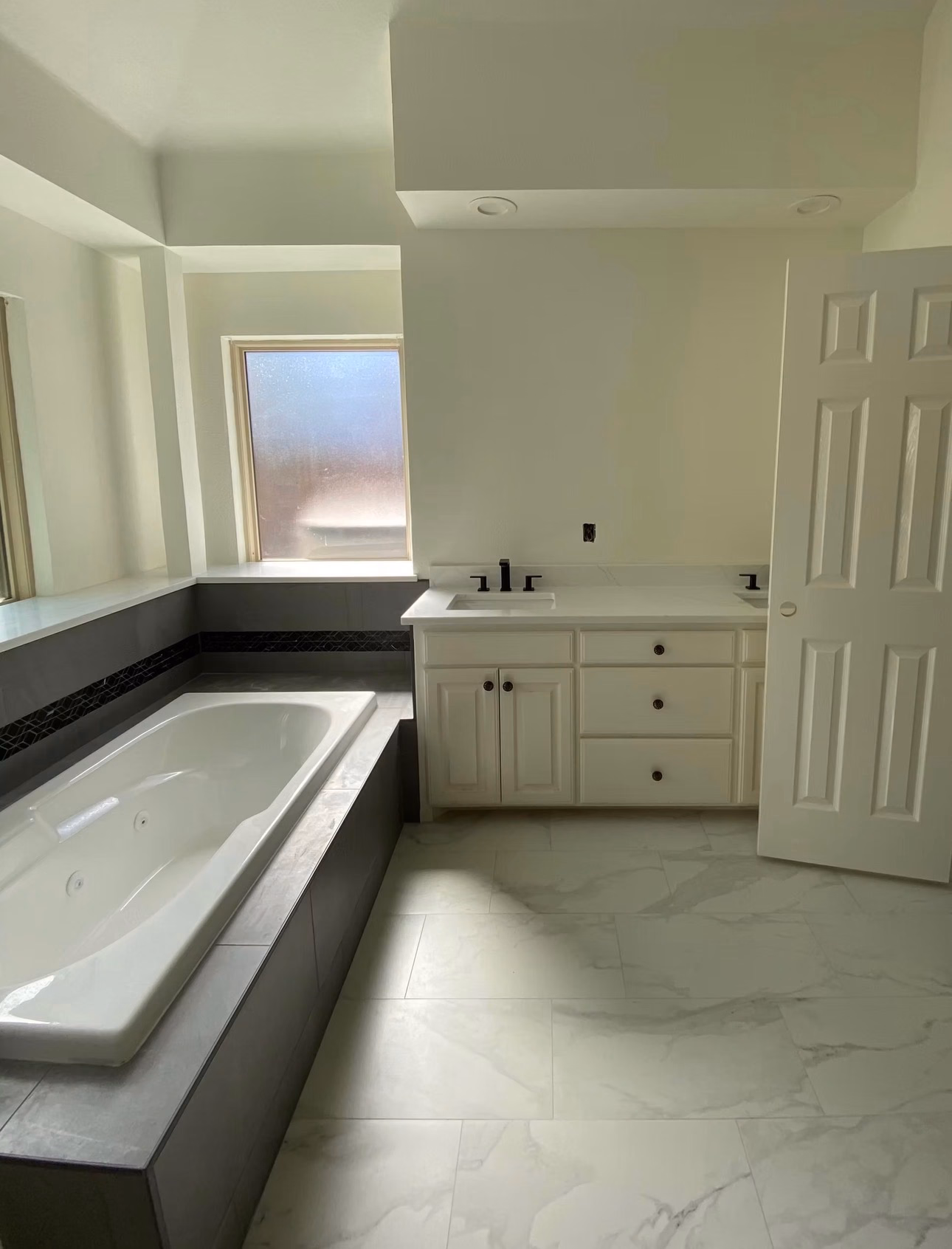 Complete bathroom refresh featuring fresh paint, new floor tile, a tiled tub surround, and a new vanity